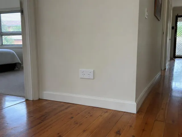 Wall-mounted double power point on a cream hallway wall with timber floorboards in Dee Why