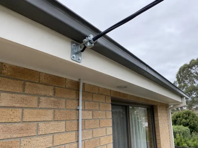 Overhead service cable and metal point-of-attachment bracket on a brick house exterior in Allambie Heights